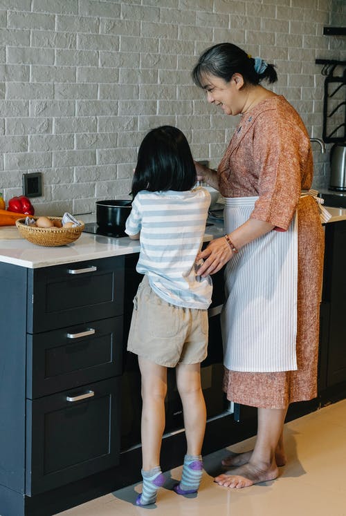 教小孙女做饭的微笑亚洲祖母 · 免费素材图片