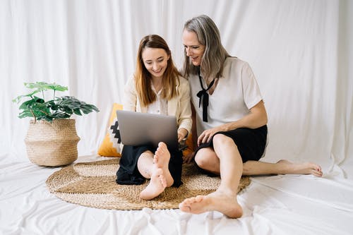 坐在床上拿着白色陶瓷杯的白衬衫的女人 · 免费素材图片