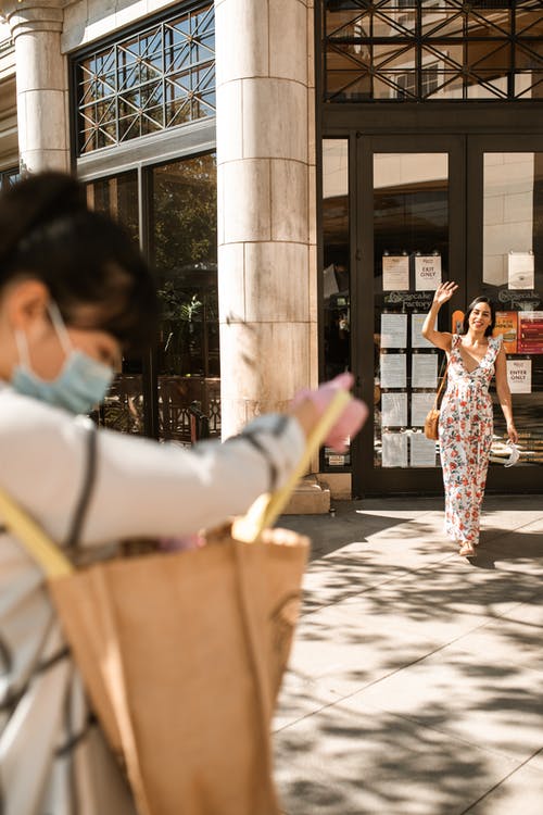 拿着智能手机的白夹克和粉红色花裤子的女人 · 免费素材图片