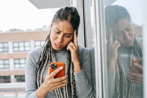 疲倦的黑女人浏览手机 · 免费素材图片