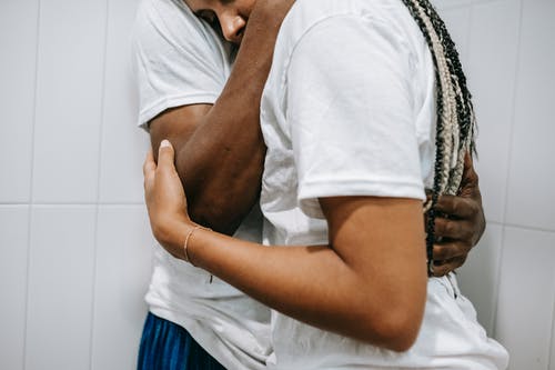 裁剪无法辨认的休闲黑人夫妇在浴室争吵后拥抱 · 免费素材图片