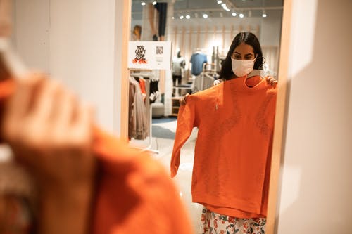 橙色长袖衬衫站在镜子旁边的女人 · 免费素材图片