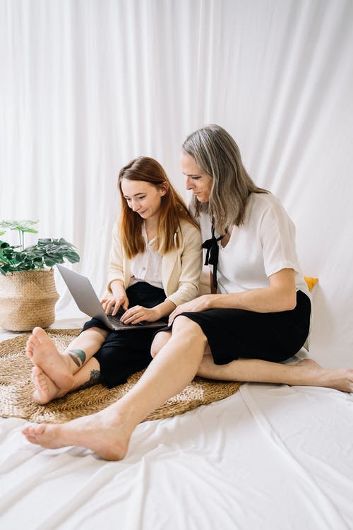 白色长袖衬衫和黑色的裙子，坐在白色的床上的女人 · 免费素材图片