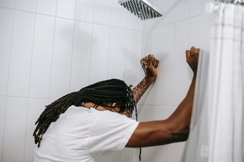 无法识别沮丧的黑人男子，在淋浴的水流下 · 免费素材图片