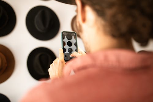 持有白色和黑色遥控器的人 · 免费素材图片