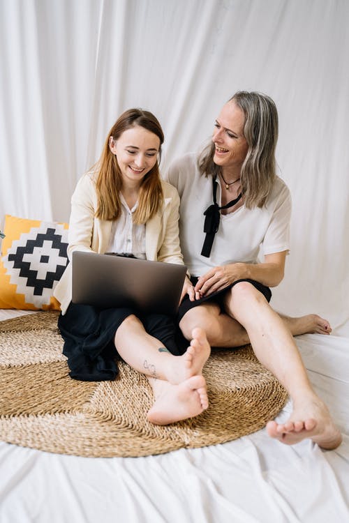 2名妇女坐在棕色和米色碎花沙发上 · 免费素材图片