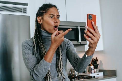 富有表现力的年轻黑人女士在智能手机上的视频对话期间争论 · 免费素材图片