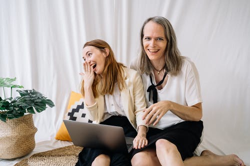 2名妇女坐在棕色和白色的花沙发上 · 免费素材图片