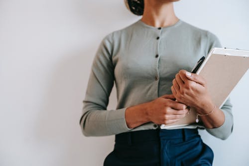 站立与剪贴板的妇女对白墙 · 免费素材图片