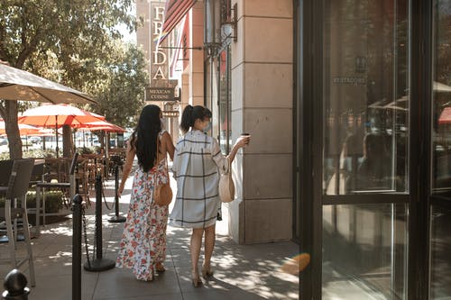 站在白衬衫的女人旁边的白色和红色花裙子的女人 · 免费素材图片