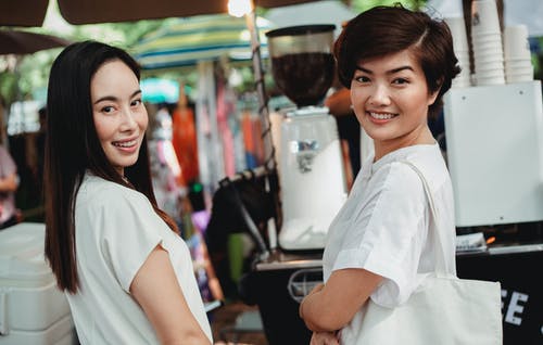 站立在街道食堂柜台附近的微笑的亚裔妇女 · 免费素材图片