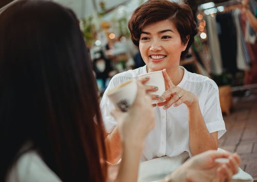 积极的亚洲妇女聊天，在大街上享受热饮 · 免费素材图片