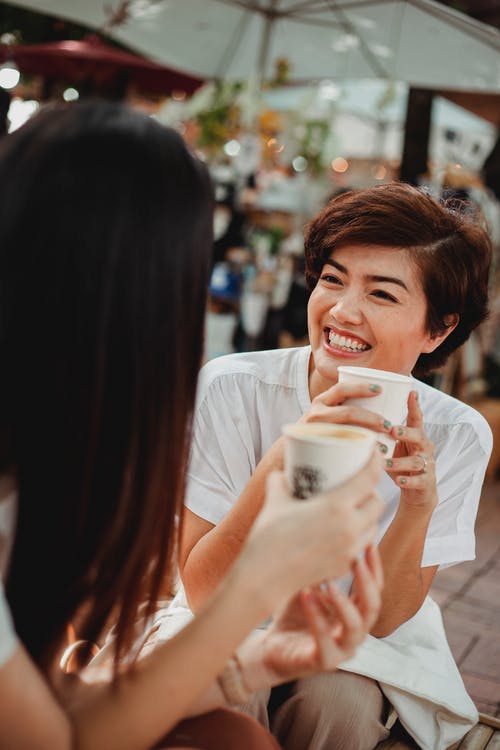 性格开朗的亚裔妇女在室外自助餐厅喝咖啡 · 免费素材图片
