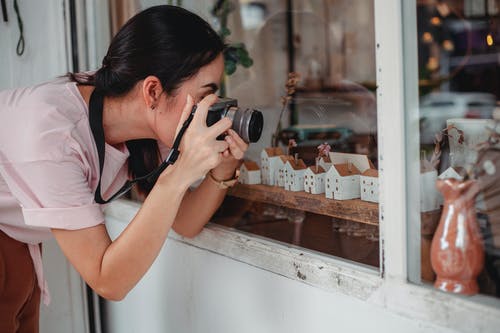 面带笑容的女摄影师拍照的商店展示柜在相机上 · 免费素材图片