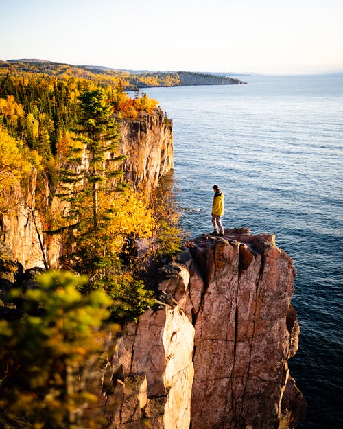 在秋天的阳光下的岩石峭壁上的人 · 免费素材图片