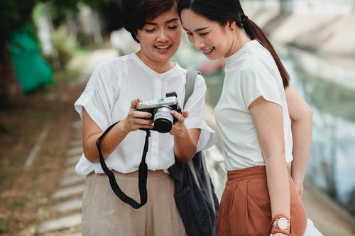 裁剪族裔女人与微笑的最好的朋友分享相机拍照 · 免费素材图片