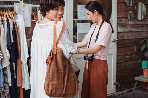 播种微笑的亚裔女子和纺织袋靠近女友 · 免费素材图片