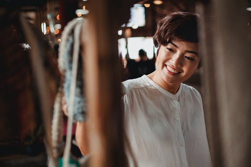 在纪念品市场上收获微笑的亚裔妇女选择礼物 · 免费素材图片