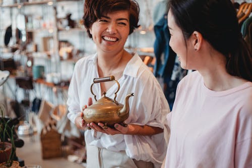 用水壶在商店里聊天收获快乐的亚洲买家 · 免费素材图片