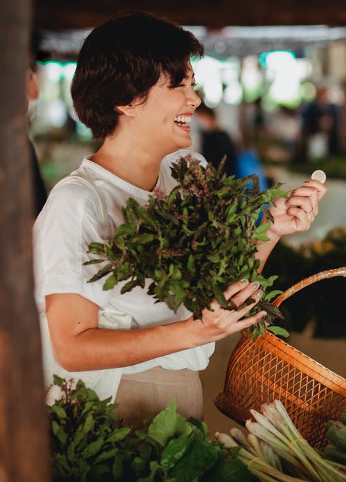 快乐的亚洲买家与捆绑的海湾叶子在市场上 · 免费素材图片