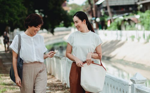 快乐的亚洲女友在街上行走时交谈 · 免费素材图片