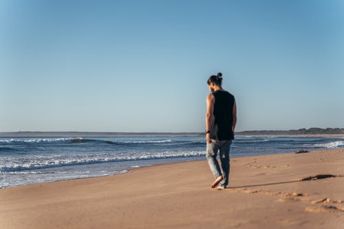 在空的沙滩上行走的匿名男子 · 免费素材图片