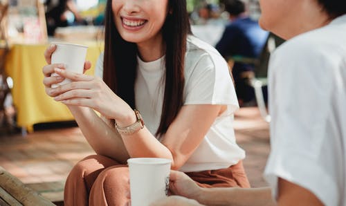 播种在阳光明媚的街道上喝咖啡的快乐妇女 · 免费素材图片