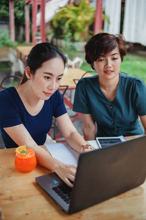 亚洲妇女浏览在咖啡馆的笔记本电脑 · 免费素材图片