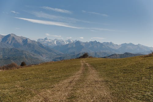 在蓝天下的山脉附近的绿草田 · 免费素材图片