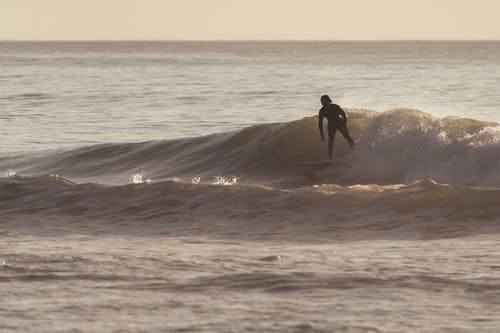 在强大的海洋波上冲浪的人 · 免费素材图片
