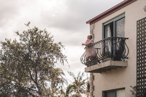 女人站在阳台上的栅栏 · 免费素材图片