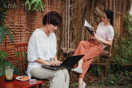 亚洲女友与笔记本电脑和杂志在花园里 · 免费素材图片