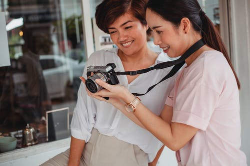 裁剪快乐的亚洲女友分享在城市街道上的相机拍照 · 免费素材图片