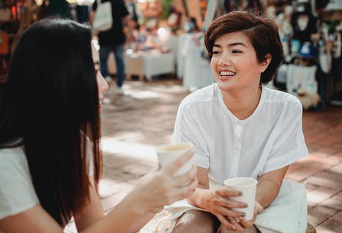 性格开朗的亚裔妇女享受咖啡和在户外咖啡馆聊天 · 免费素材图片