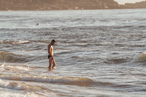 站立在挥动的海水的游泳裤的人 · 免费素材图片