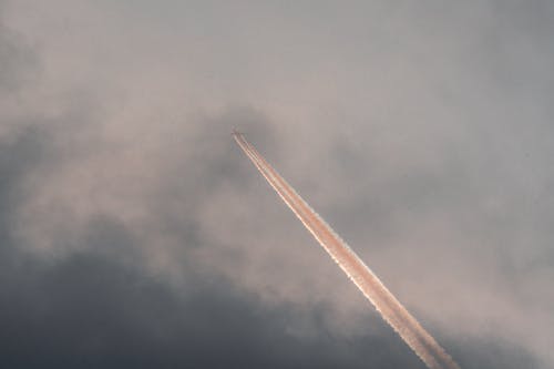 飞机在阴天傍晚的天空中飞行 · 免费素材图片