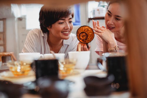 高兴的年轻亚洲妇女在现代商店中选择杯子 · 免费素材图片