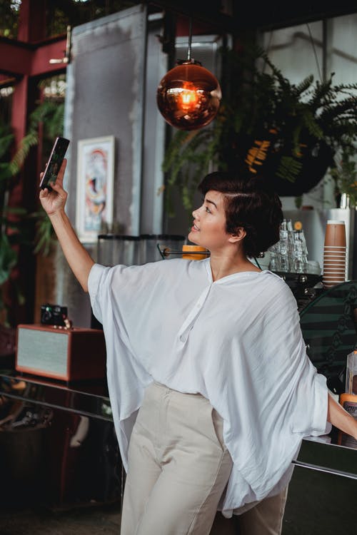 采取在智能手机的快乐的妇女selfie在咖啡馆 · 免费素材图片