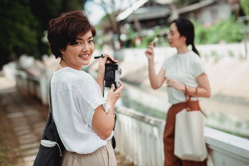 拍朋友的照片微笑的亚裔妇女照相机的 · 免费素材图片