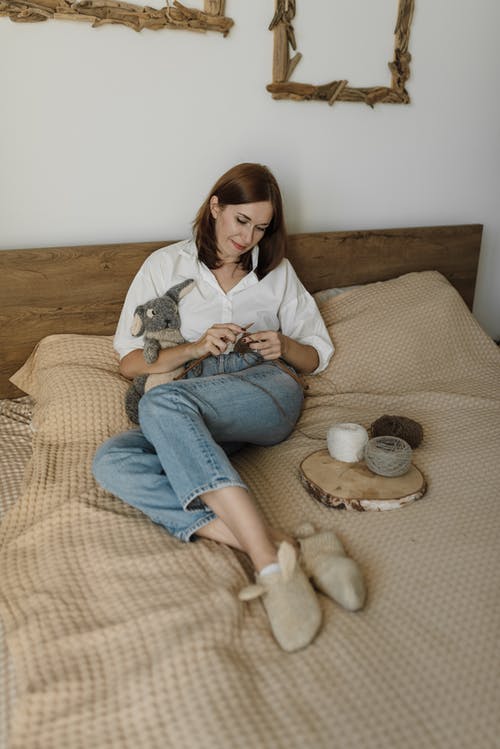 白衬衫和蓝色牛仔牛仔裤，坐在棕色的沙发上的女人 · 免费素材图片