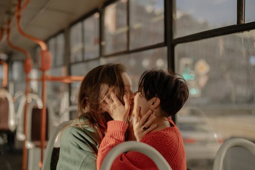 红色针织毛衣亲吻绿色衬衫的女人的女人 · 免费素材图片