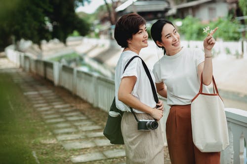 显示用手指的美满的亚裔妇女在女性朋友附近 · 免费素材图片