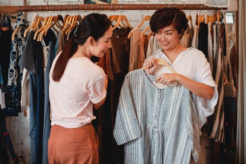 高兴的亚洲购物者在服装店中选择服装 · 免费素材图片