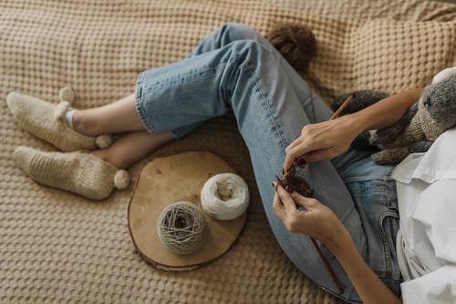 拿着白色和棕色贝壳的蓝色牛仔牛仔裤的人 · 免费素材图片