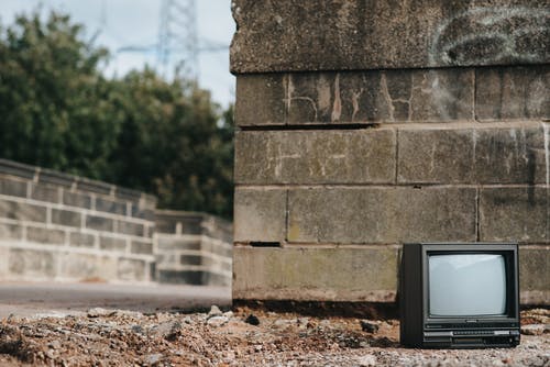 棕色混凝土墙上的黑色crt电视 · 免费素材图片