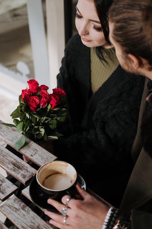 拿着红色玫瑰花束的黑羊毛衫的女人 · 免费素材图片
