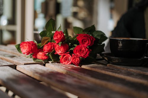棕色的木桌上的红玫瑰 · 免费素材图片