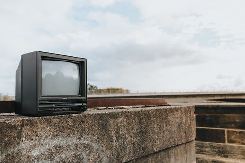 在白云下的棕色场上的黑色crt电视 · 免费素材图片