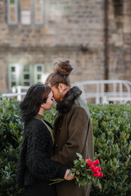 男人和女人在绿色的植物附近接吻 · 免费素材图片