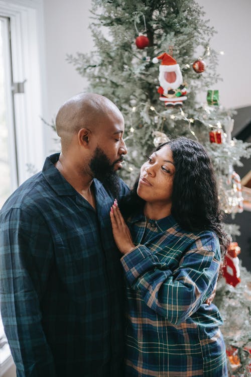 爱拥抱在圣诞树附近的黑人夫妇 · 免费素材图片